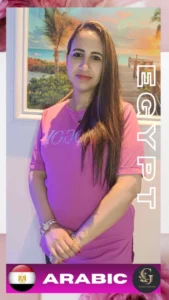 Arabic-speaking female massage therapist from Egypt wearing a pink shirt, standing in front of a beach painting with hands gently clasped, representing Egyptian staff at Asian Golden Spa in Ras Al Khaimah; offering Arabic language support for full body and oil massage in Nakheel spa center.