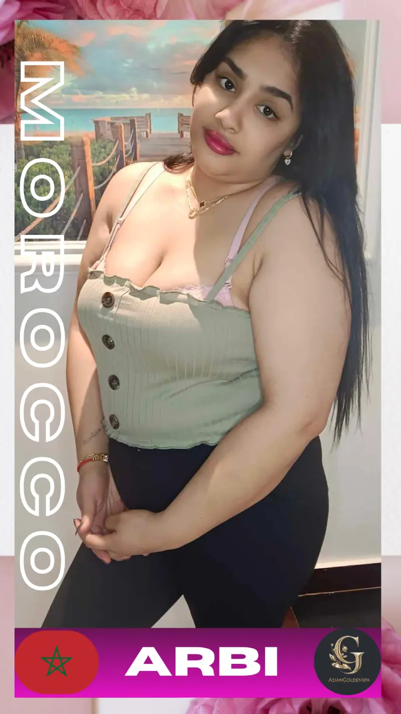 Moroccan woman posing confidently in a sleeveless green top with button details and black pants, standing indoors with a beach-themed wall art in the background. She has long black hair, red lips, and is accessorized with gold jewelry. The image includes the Moroccan flag, the word "ARBI", and the Asian Golden Spa logo. Promotional material for Asian Golden Spa in Ras Al Khaimah.
