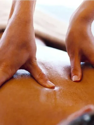 Close-up view of a professional therapist performing a deep tissue back massage using both thumbs at Asian Golden Spa in Ras Al Khaimah. The therapist's hands apply firm pressure to the client's